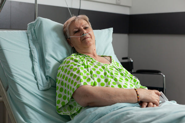 Woman lying in a hospital bed with an oxygen tube, wearing a green polka dot shirt. Photo by Freepik.