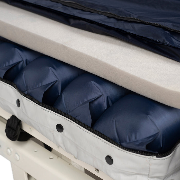 A close-up view of the Proactive Protekt 1st Defense mattress system displaying the individual air bladders and a layer of foam within its blue and white cover, unzipped to reveal the internal structure