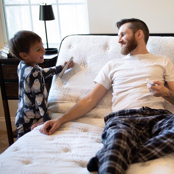 Father and child interacting with the Flexabed Premier adjustable bed remote, demonstrating easy control and family-friendly comfort