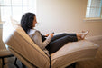 A smiling woman reclines on the customizable Flexabed Value-Flex adjustable bed, holding a remote control to adjust her position
