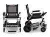 A two-panel product image showing the Zoomer from a direct front view (left) and a direct side profile (right). These views highlight the chair's slim profile, the rear anti-tipper wheels, and the low-profile motor housing between the rear wheels.