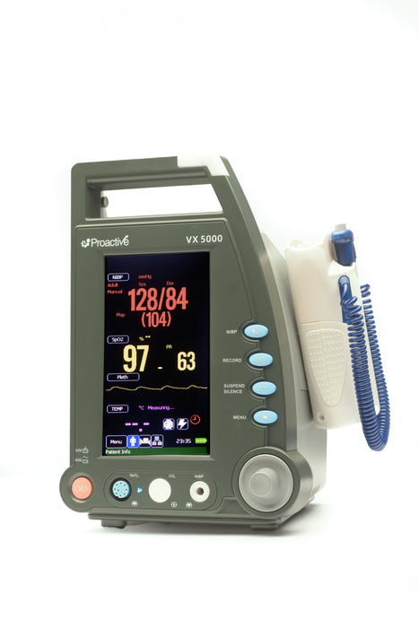 Protekt VX 5000 vital signs monitor powered on, showing blood pressure, SpO₂, pulse rate, and temperature readings on a bright color display