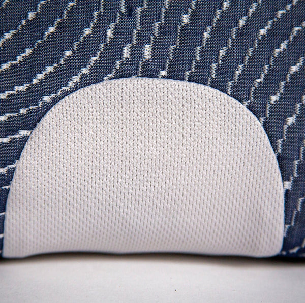 An extreme close-up of a circular, white mesh ventilation "breathability" port embedded in the textured navy blue side fabric.