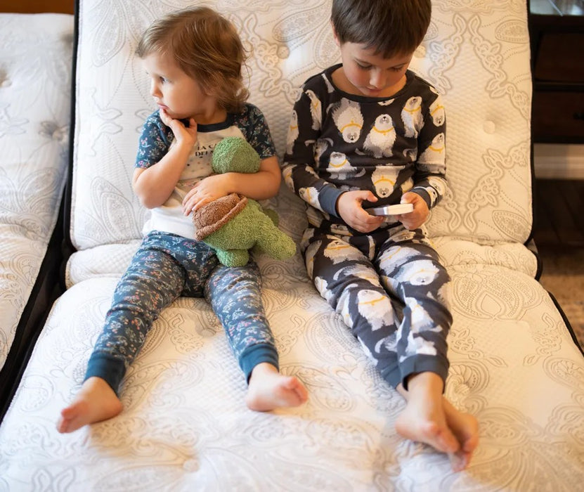 Two young children sitting on a Flexabed Premier adjustable bed, highlighting soft mattress comfort and kid-safe design
