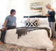 Couple smiling with a Flexabed Premier adjustable bed between them, a man is sitting near the foot of the bed while a woman is standing on the right side