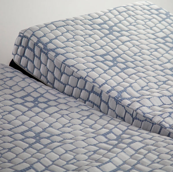 A high-angle close-up focusing on the seam of the split-head mattress, showing how the two sections move independently while maintaining the same textured cover.