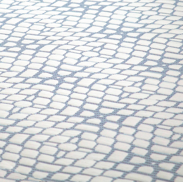 An extreme close-up of the top fabric, featuring a white, quilted "cobblestone" or tiled pattern outlined with subtle blue stitching.