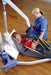 A woman in a hospital bed is comfortably assisted by the Joerns Hoyer Advance Electric Patient Lift, a compact folding floor lift that ensures safe movement and added support.