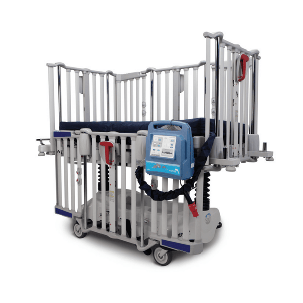 An infant crib with the Dolphin Fluid Immersion Simulation (FIS) Mattress System. The crib has tall, light-colored side rails and a dark blue mattress cover. The blue Dolphin Pediatric control unit is attached to the exterior of the rail.