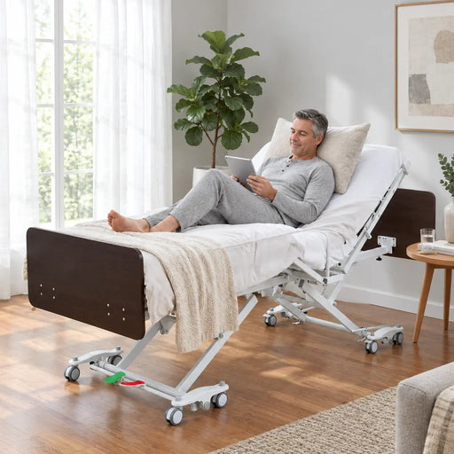 Fully electric expandable hospital bed for home use - Emerald Oasis 52300 with hi-low height adjustment, adjustable backrest raised, dark espresso headboard and footboard, white Double Y frame, and central locking pedals in a modern living room setting