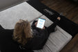 Woman sitting on a Flexabed Hi-Low adjustable bed with optional mattress while using the Okin SmartBed app on a tablet to adjust the bed 
