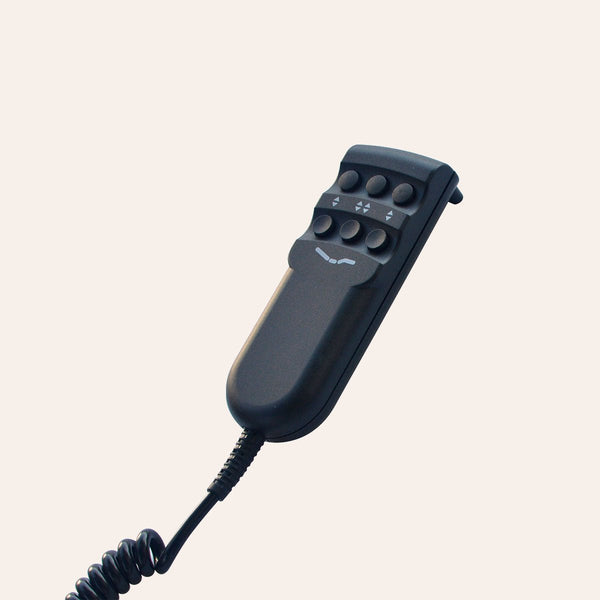 A wired hand remote for a Flexabed Value-Flex, shown at a three-quarter angle against an off-white background. The ergonomic, matte black device features six circular buttons in two rows of three, separated by small white directional arrows. A reclining bed icon is printed below the buttons, and a thick, black coiled cord extends from the base.