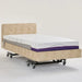 Front-facing angled view of the iCare IC333EL bed featuring a beige tufted fabric headboard and upholstered base. The extra-long mattress extension is visible at the foot of the bed, designed to provide additional length for taller users.