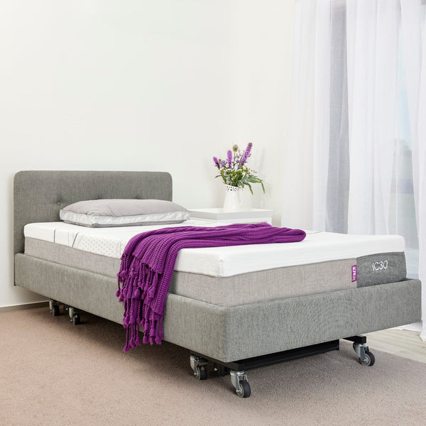 Icare IC333 in Smoke with headboard, IC30 mattress, an Icare pillow, and a purple blanket in a room with white walls and curtains.