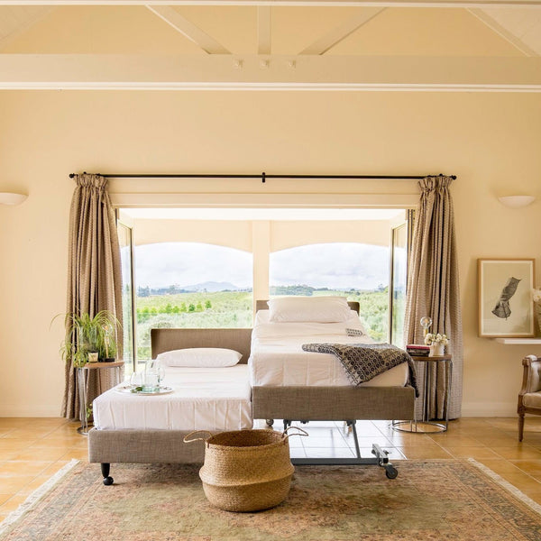 The Icare dual king/partner setup in a modern bedroom with a large window view and warm lighting.