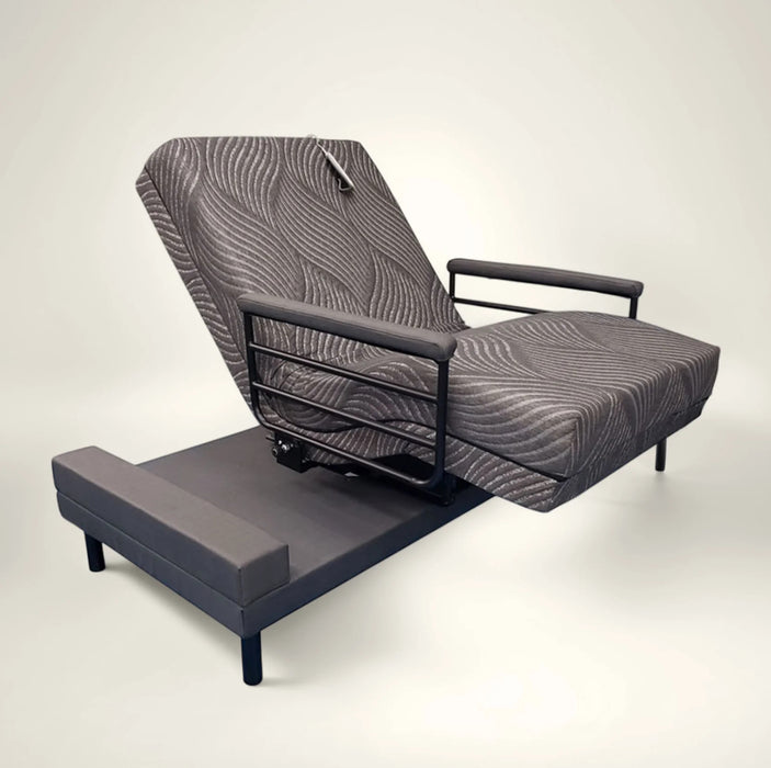 The UPbed Independence Adjustable Bed for Seniors by Journey Health features patterned gray upholstery, a raised backrest, black metal side rails, and armrests, shown against a plain light background.