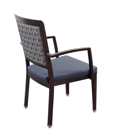 Dining chair with arms for assisted living furniture - aluminum wood grain frame with patterned square backrest and blue upholstered seat cushion, featuring armrests and metal floor glides, angled view on white background