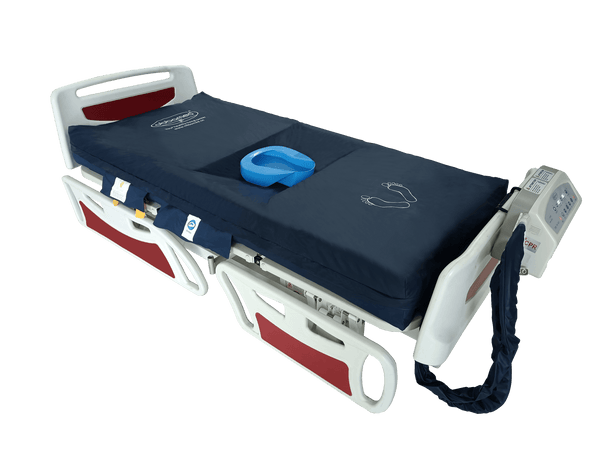 A high-resolution photo of the ObboMed OB-1620 medical air mattress system against a transparent background. The navy blue mattress is shown on a white and red hospital bed frame. It features a central recessed area with a blue bedpan, white foot-placement icons at the base, and a control unit mounted on the footboard with a thick blue air hose connecting to the mattress.