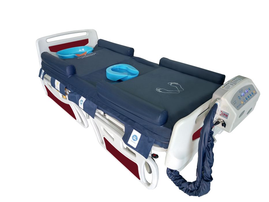 A high-quality photograph of the OB-1680 alternating air mattress system. The navy blue mattress is shown with its inflatable guardrails raised, a blue bedpan in the center, and a light blue shampoo basin at the head. The control unit is attached to the foot of the white and red bed frame, with a CPR emergency release tag clearly visible on the side of the pump.