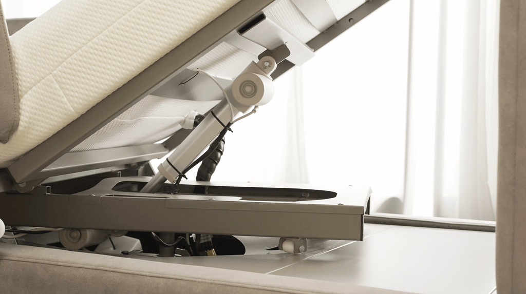 Close-up of the Starsleep Orin Rotating Bed’s mechanical base and metal frame, showing its support structure with the mattress partially raised. Light curtains appear in the background.