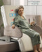 An older woman in silk pajamas relaxes on the Starsleep Orin Rotating Bed with air massage and heating features, holding a remote. The chair’s backrest displays highlighted massage and heat symbols.