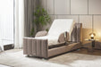 The Starsleep Orin Rotating Bed, featuring a padded beige frame and white mattress, is shown in a stylish room with a plant, floor-length curtains, and a small round side table with a lamp.
