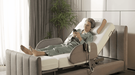 An older woman in pajamas relaxes on the Starsleep Orin Rotating Bed with its elevated backrest, using her smartphone. The bed includes a remote control, a nearby green plant, and soft daylight streaming through the window.