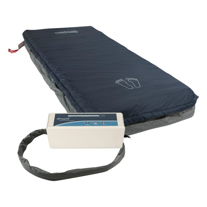 Protekt Aire 4600DX mattress system complete setup showing dark blue alternating pressure mattress with foot outline marking, connected to white control unit via flexible air tubing for hospital bed applications