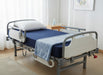A hospital room setting showing a medical bed with the dark blue Proactive Protekt HC 50 foam mattress with cover installed. A pillow and a light blue blanket are visible, and the bed is empty