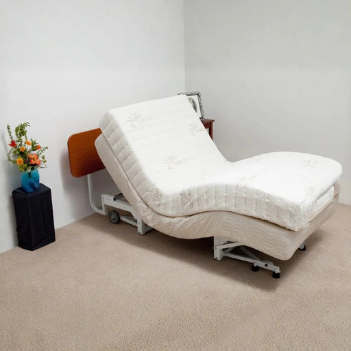 Supernal 5 adjustable bed with cherry headboard in a room with a small table and flowers.
