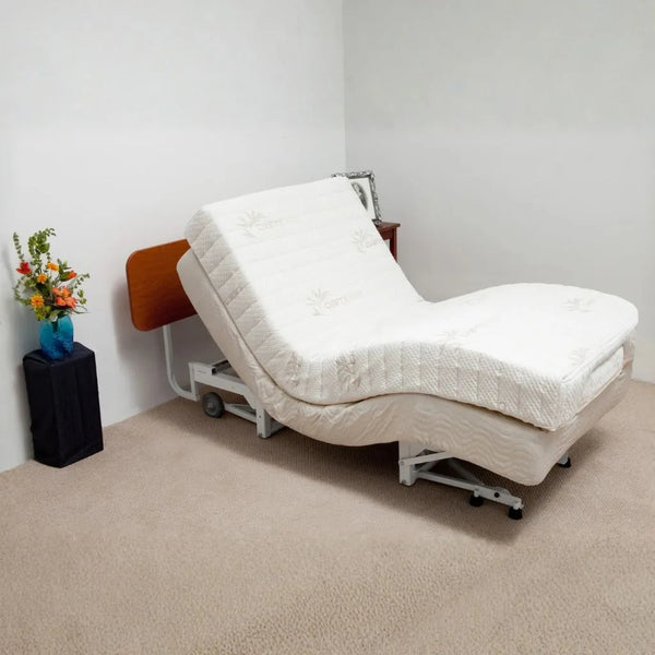Supernal 5 adjustable bed with cherry headboard in a room with a small table and flowers.