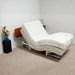 Supernal 5 adjustable bed with cherry headboard in a room with a small table and flowers.