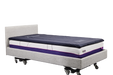 A side-angle, full-length view of an IC333 adjustable bed fitted with a dark blue ActiveFloat medical mattress overlay, showcasing the complete bed assembly.