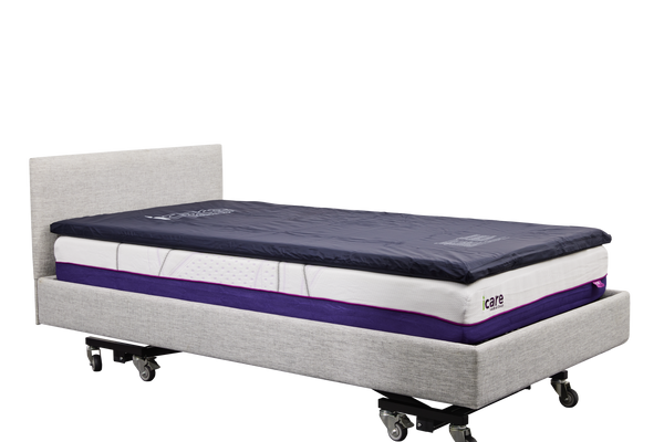 A side-angle, full-length view of an IC333 adjustable bed fitted with a dark blue ActiveFloat medical mattress overlay, showcasing the complete bed assembly.