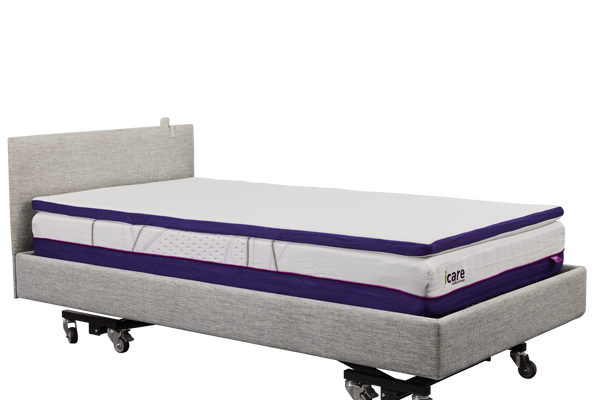 A side-angle, full-length view of an IC333 adjustable bed with a white, plush ActiveX mattress overlay placed on top of the main mattress.
