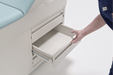 Detailed view of the side storage drawers on the Graham-Field Hausted 4200 Series. A staff member is shown opening one of the large, easy-glide drawers, which are designed for organized access to medical supplies and patient gowns.