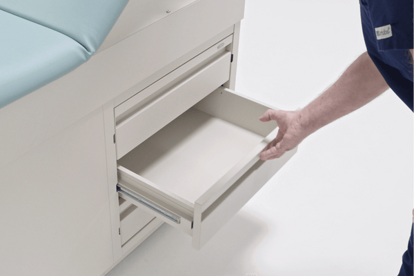Detailed view of the side storage drawers on the Graham-Field Hausted 4200 Series. A staff member is shown opening one of the large, easy-glide drawers, which are designed for organized access to medical supplies and patient gowns.