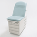 Three-quarter studio view of the Graham-Field Hausted 4200 Series Manual Exam Table in a light teal upholstery. The table features a high-back adjustable backrest, a modular base with integrated storage drawers on the side and front, and a streamlined, medical-grade finish.