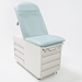 Three-quarter studio view of the Graham-Field Hausted 4200 Series Manual Exam Table in a light teal upholstery. The table features a high-back adjustable backrest, a modular base with integrated storage drawers on the side and front, and a streamlined, medical-grade finish.