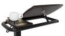 A close-up, side-angle view of the Icare over bed table, highlighting the tilting mechanism underneath the wood-grain surface. A white mug sits on the adjacent fixed side tray.