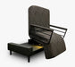The UPbed Independence Adjustable Bed for Seniors by Journey Health features a black patterned upholstery, raised backrest, mechanical lift system, and short black legs, resembling a rotating bed. Shown against a plain white background.