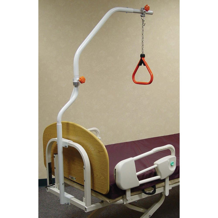 Full Joerns trapeze set attached to a hospital bed. A white metal arch extends over the bed with an adjustable chain and a red triangular handle hanging down. The bed has a light wood-grain headboard and Joerns F17 assist rails.