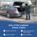 A person easily lifting the folded 42 lb Journey Air 2026 power wheelchair into the trunk of a sedan. Text overlays highlight: "Weighs only 42 lbs," "Folds in seconds," "Rolls like a suitcase when folded," and "FAA-compliant."