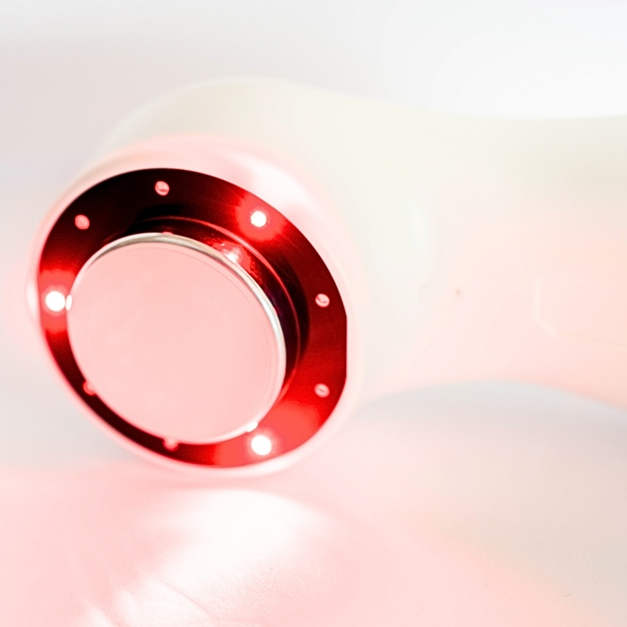 Close-up view of Oceanus Lasonic therapy device treatment head with infrared/red light laser illuminated around circular head