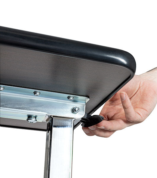Hand adjusting the height adjustment lever on an overbed table with a wooden tabletop and steel legs