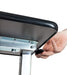 Hand adjusting the height adjustment lever on an overbed table with a wooden tabletop and steel legs