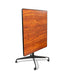 Square tilt top dining table upright showing full Biltmore Cherry wood grain surface with black metal base and wheel casters