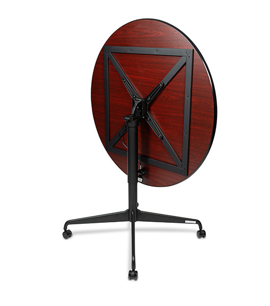 Tilt top dining table in tilted vertical position showing Biltmore Cherry wood grain top with black metal folding base and casters