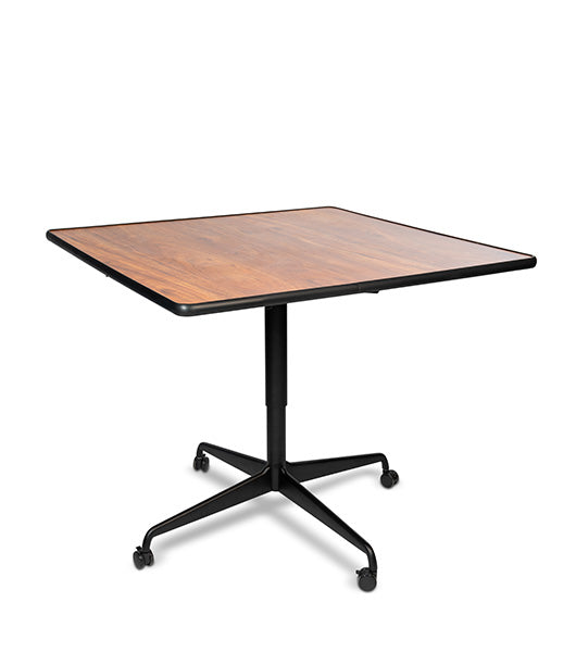 Square tilt top dining table with Biltmore Cherry wood grain surface and black metal base featuring four-wheel casters