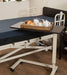 Adjustable overbed table with Mahogany surface positioned over hospital bed with meal tray